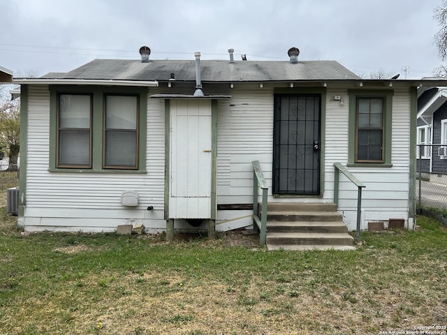 back of house featuring entry steps, central air condition unit, a lawn, and roof with shingles