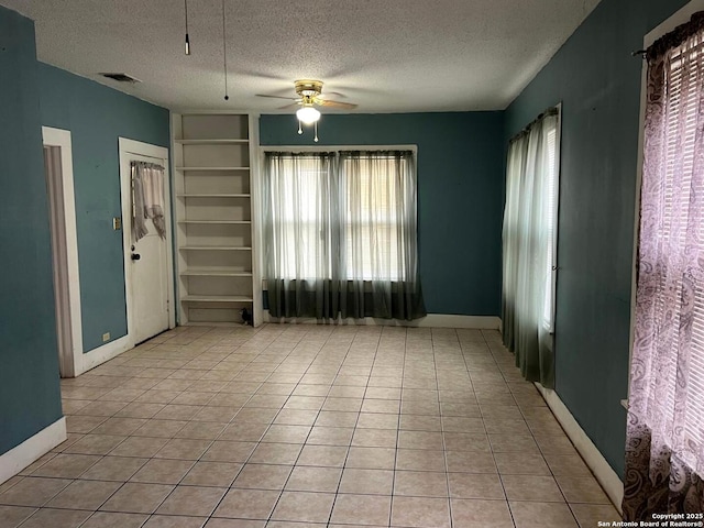 spare room with light tile patterned floors, visible vents, a wealth of natural light, and a ceiling fan