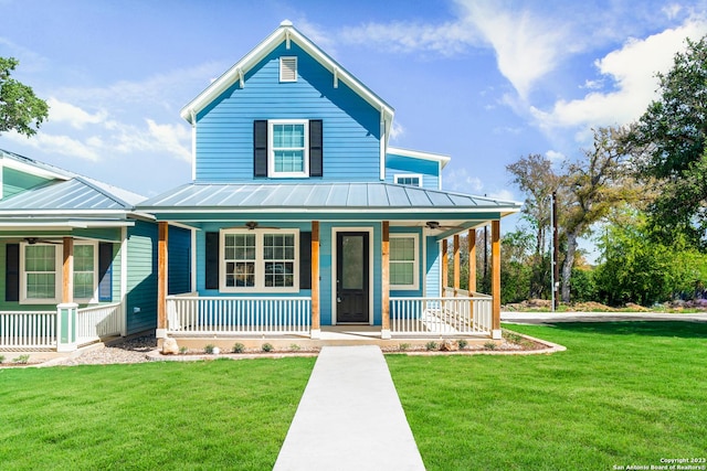view of front of house with a front yard, covered porch, metal roof, a ceiling fan, and a standing seam roof