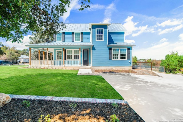 view of front of house with fence, a front yard, covered porch, metal roof, and a standing seam roof