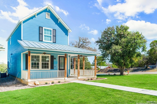 view of front of house with metal roof, covered porch, a front yard, and a standing seam roof