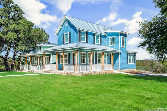 farmhouse with metal roof, a porch, a front yard, and a standing seam roof
