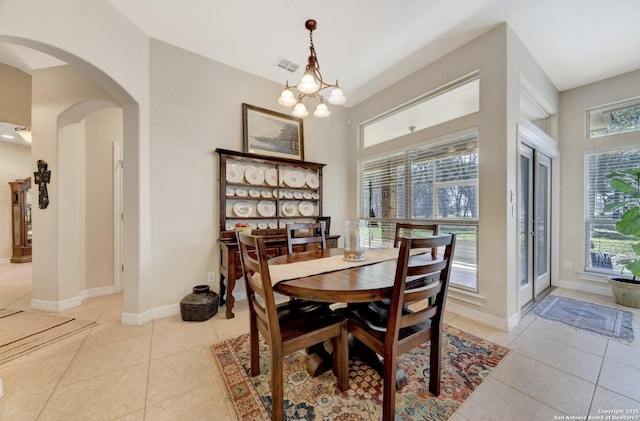 dining space with arched walkways, baseboards, and light tile patterned floors