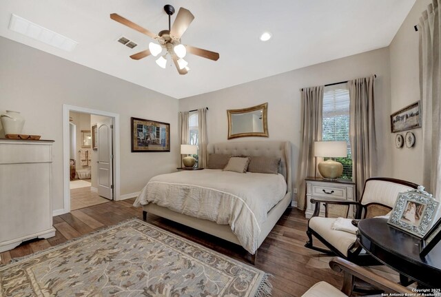 bedroom featuring baseboards, visible vents, wood finished floors, and ensuite bathroom