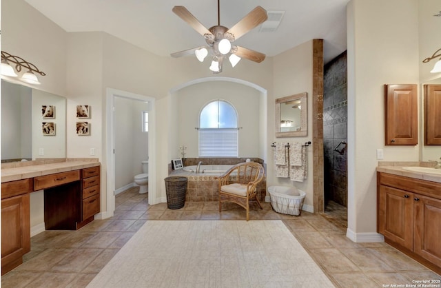 full bath with toilet, a walk in shower, vanity, a garden tub, and ceiling fan