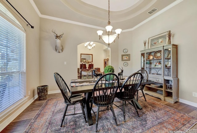 dining space featuring a raised ceiling, a chandelier, wood-type flooring, baseboards, and visible vents