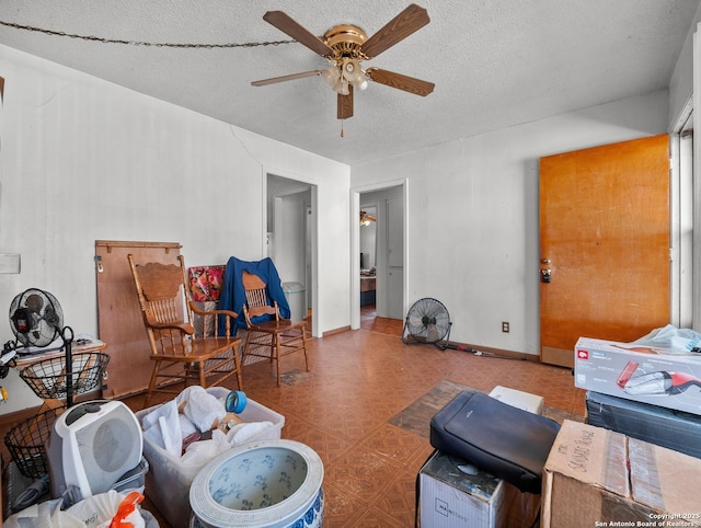 living area featuring a textured ceiling, ceiling fan, and baseboards