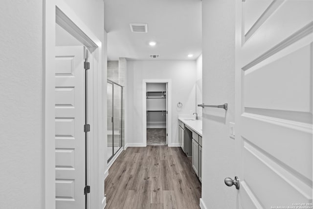 2074 Newforest Peak, New Braunfels, TX 78130 - full bathroom with a walk in closet, a stall shower, vanity, wood finished floors, and recessed lighting