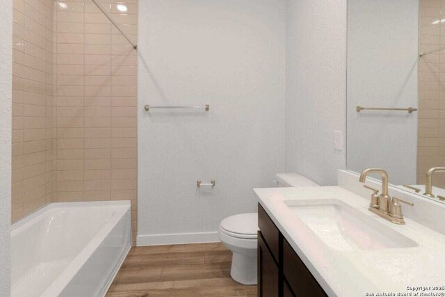 1518 Passmore Downs, New Braunfels, TX 78130 - full bathroom featuring wood finished floors, toilet, vanity, baseboards, and washtub / shower combination