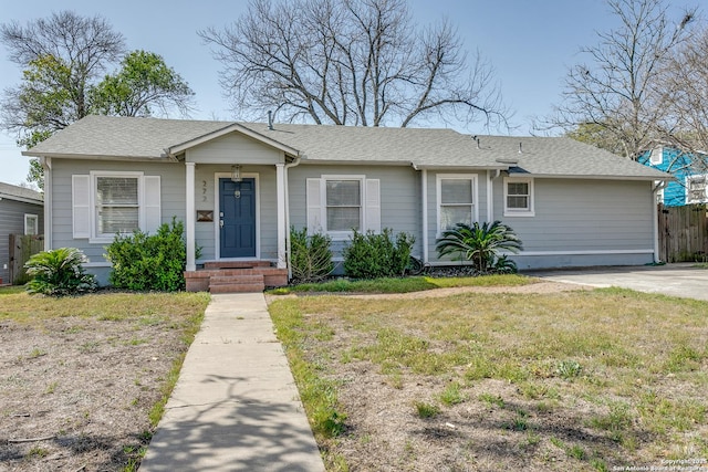 view of front facade featuring roof with shingles, a front yard, and fence