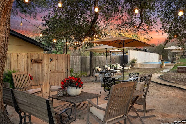 262 Rockhill Dr, San Antonio, TX 78209 - patio terrace at dusk with a fenced backyard, an outbuilding, and outdoor dining space