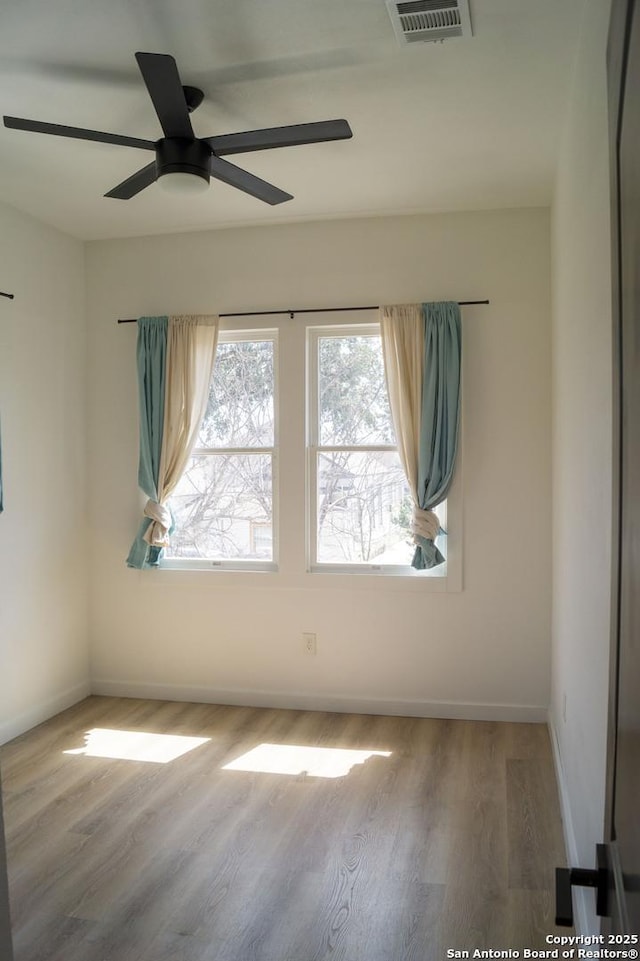 unfurnished room with wood finished floors, baseboards, ceiling fan, and visible vents