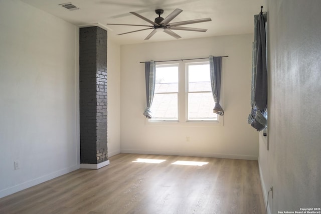 unfurnished room featuring baseboards, visible vents, a ceiling fan, and wood finished floors
