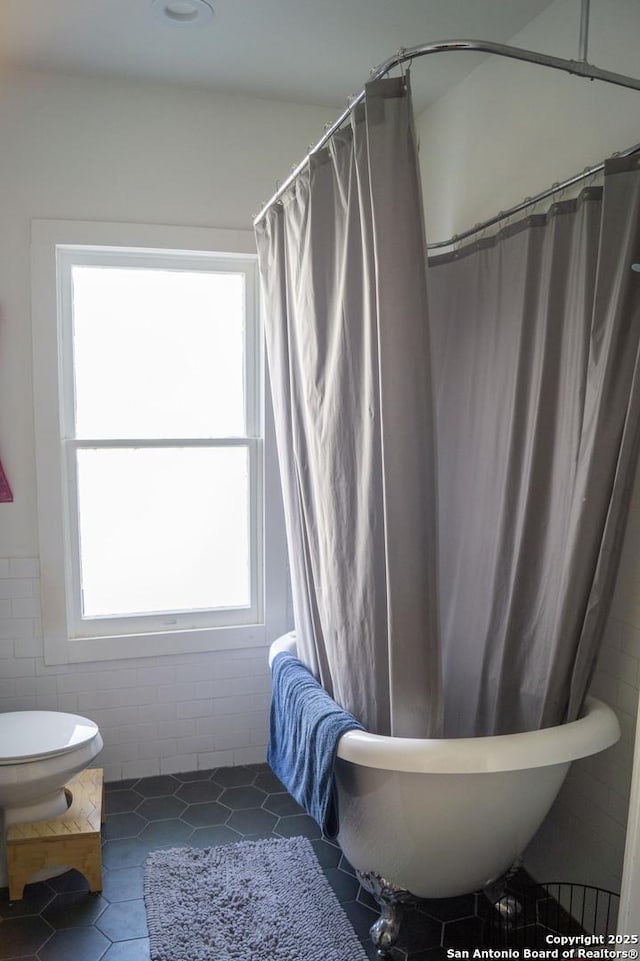 full bath featuring tile walls, a wealth of natural light, toilet, and tile patterned floors