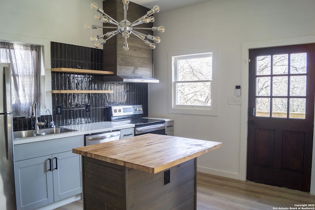 kitchen featuring open shelves, an inviting chandelier, a sink, butcher block counters, and appliances with stainless steel finishes