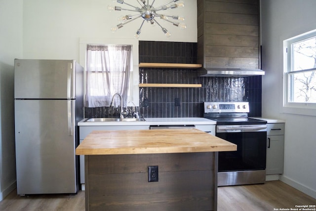 kitchen featuring wooden counters, a chandelier, a sink, and stainless steel appliances