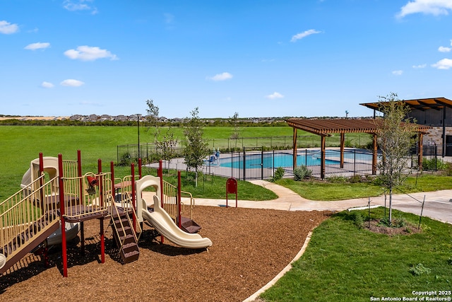 community jungle gym with a lawn, fence, and a community pool