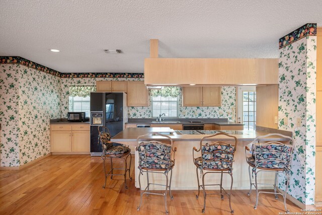 831 Hill Top, Canyon Lake, TX 78133 - kitchen with wallpapered walls, a peninsula, a sink, and light brown cabinets