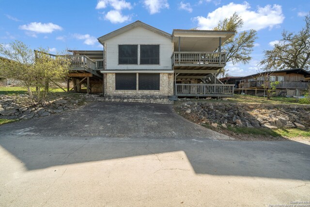 831 Hill Top, Canyon Lake, TX 78133 - view of front of home with driveway, a wooden deck, and stone siding