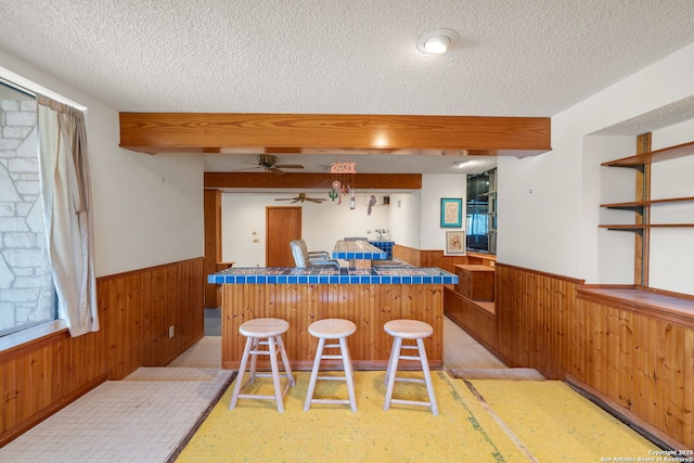 831 Hill Top, Canyon Lake, TX 78133 - kitchen featuring a wainscoted wall, a textured ceiling, a kitchen breakfast bar, and wooden walls