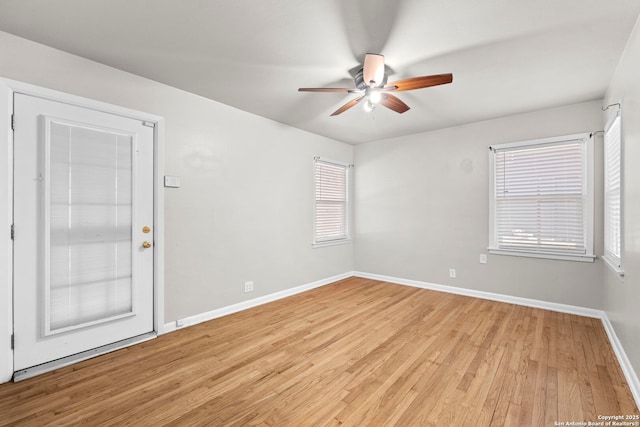 spare room featuring baseboards, light wood-style floors, and a ceiling fan