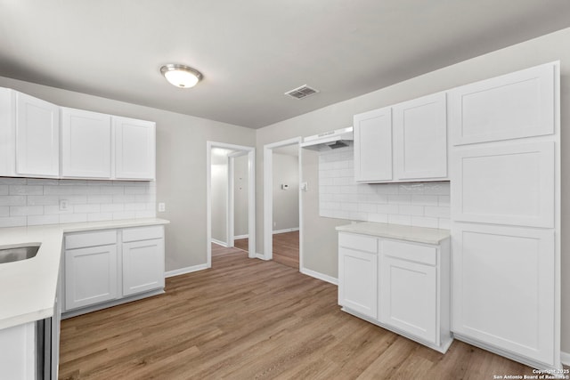 kitchen featuring light countertops, white cabinetry, light wood-type flooring, visible vents, and decorative backsplash