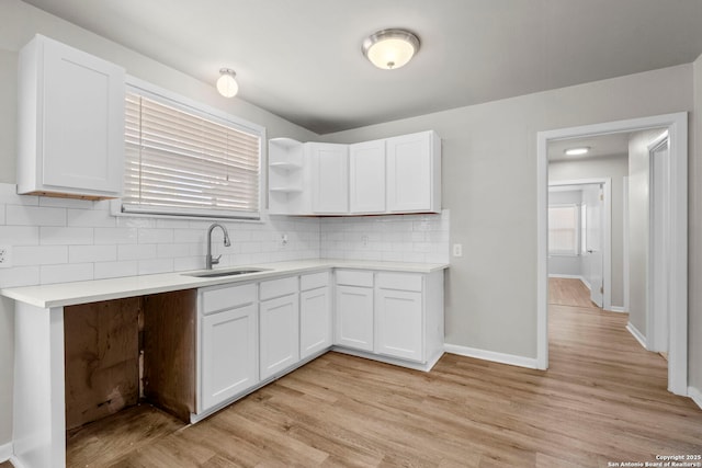 kitchen featuring white cabinetry, light countertops, decorative backsplash, and a sink