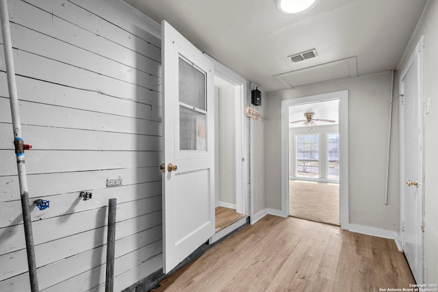 corridor with baseboards, visible vents, light wood-type flooring, and attic access