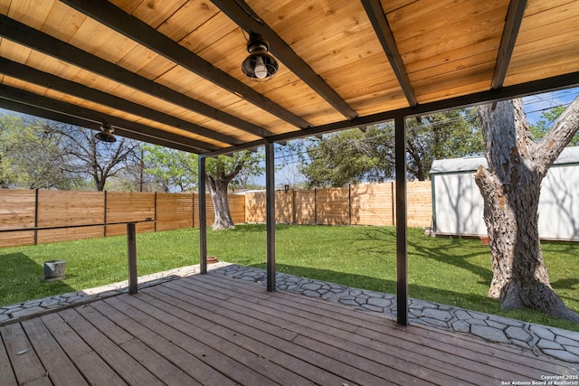 deck with a fenced backyard, an outdoor structure, a storage shed, and a yard