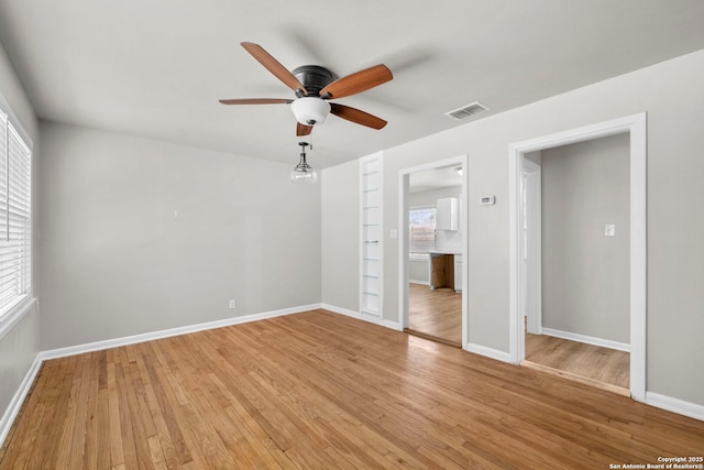 spare room with baseboards, visible vents, light wood-style flooring, and a ceiling fan