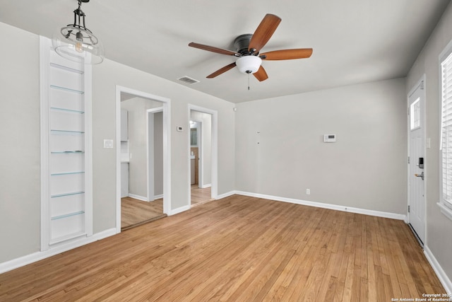 spare room with a ceiling fan, baseboards, light wood-style floors, and visible vents
