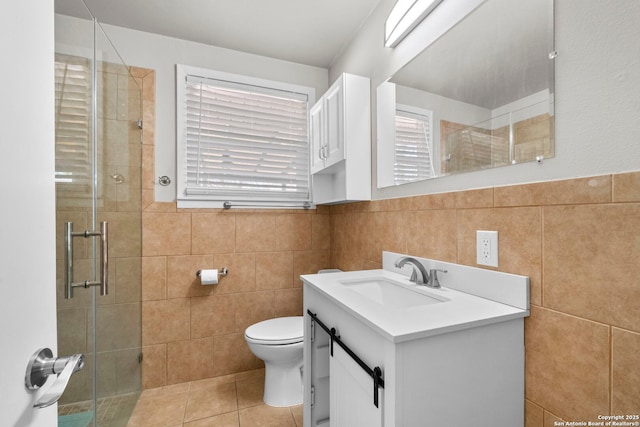 full bathroom with tile patterned flooring, vanity, tile walls, toilet, and a stall shower