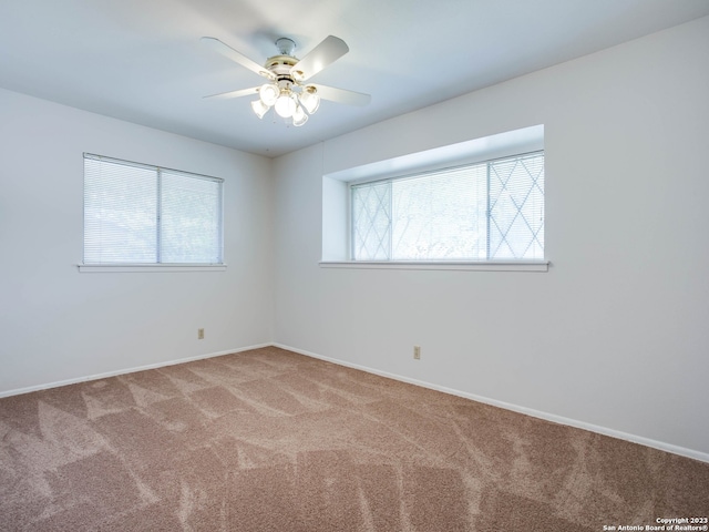 carpeted empty room featuring ceiling fan, plenty of natural light, and baseboards