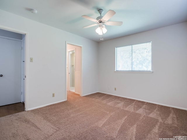 carpeted empty room featuring a ceiling fan and baseboards