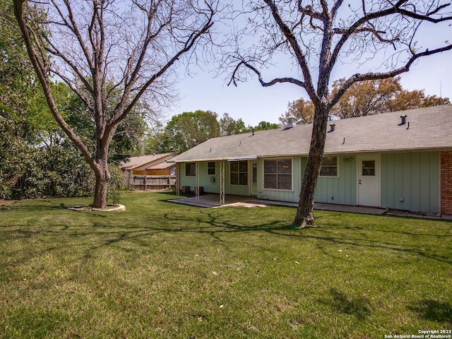 rear view of property featuring a lawn, fence, a patio area, and board and batten siding