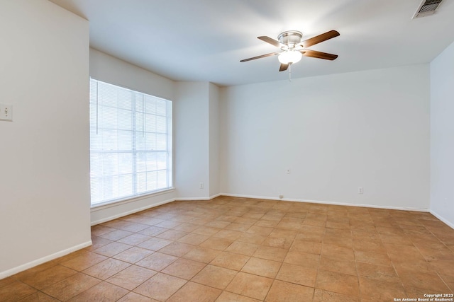 unfurnished room with baseboards, visible vents, and ceiling fan