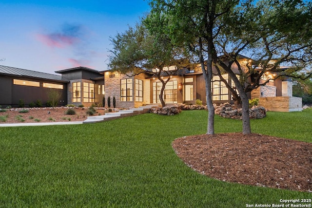 view of front of house featuring stone siding, a front yard, and stucco siding