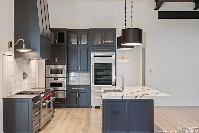 kitchen featuring decorative backsplash, appliances with stainless steel finishes, light wood-style floors, and a sink