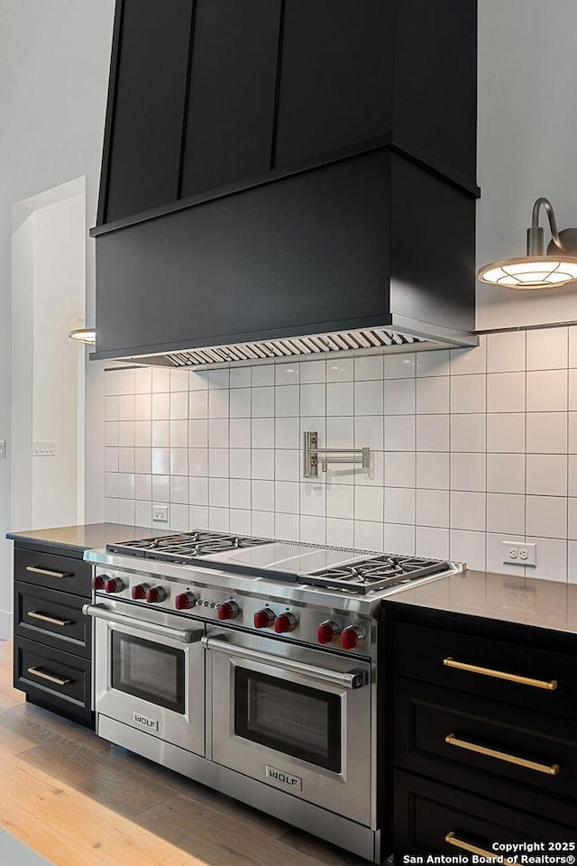 kitchen featuring range with two ovens, dark cabinets, tasteful backsplash, and wood finished floors