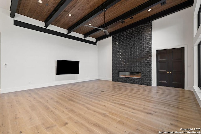 unfurnished living room with wood finished floors, a ceiling fan, beamed ceiling, wood ceiling, and a large fireplace