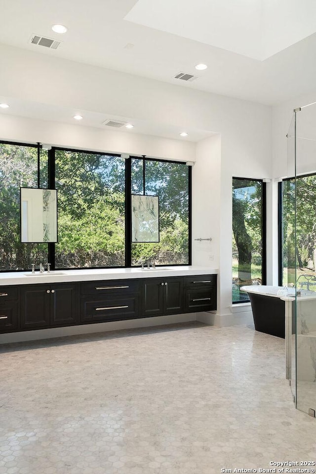 bathroom featuring recessed lighting, a freestanding tub, double vanity, and visible vents