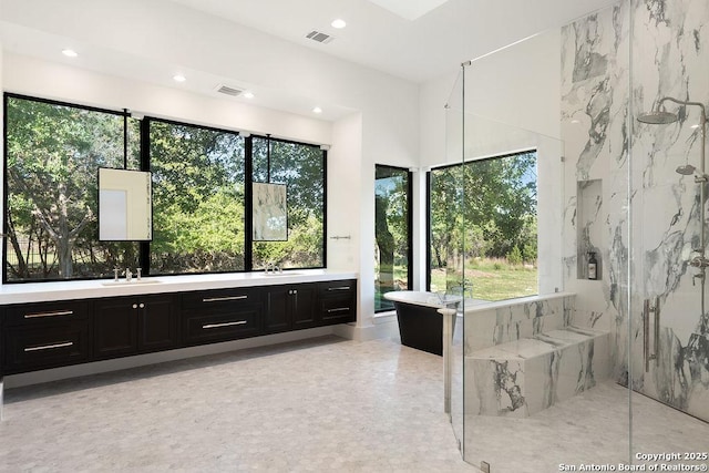 bathroom with a freestanding bath, a marble finish shower, vanity, and visible vents