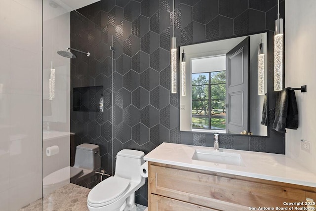 bathroom featuring tile walls, tiled shower, vanity, and toilet