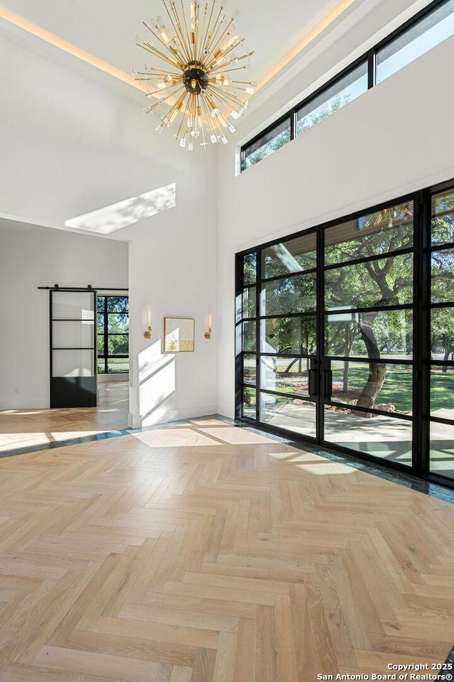 unfurnished room featuring a high ceiling, baseboards, and a notable chandelier
