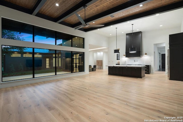 unfurnished living room featuring recessed lighting, a high ceiling, beamed ceiling, light wood-type flooring, and ceiling fan