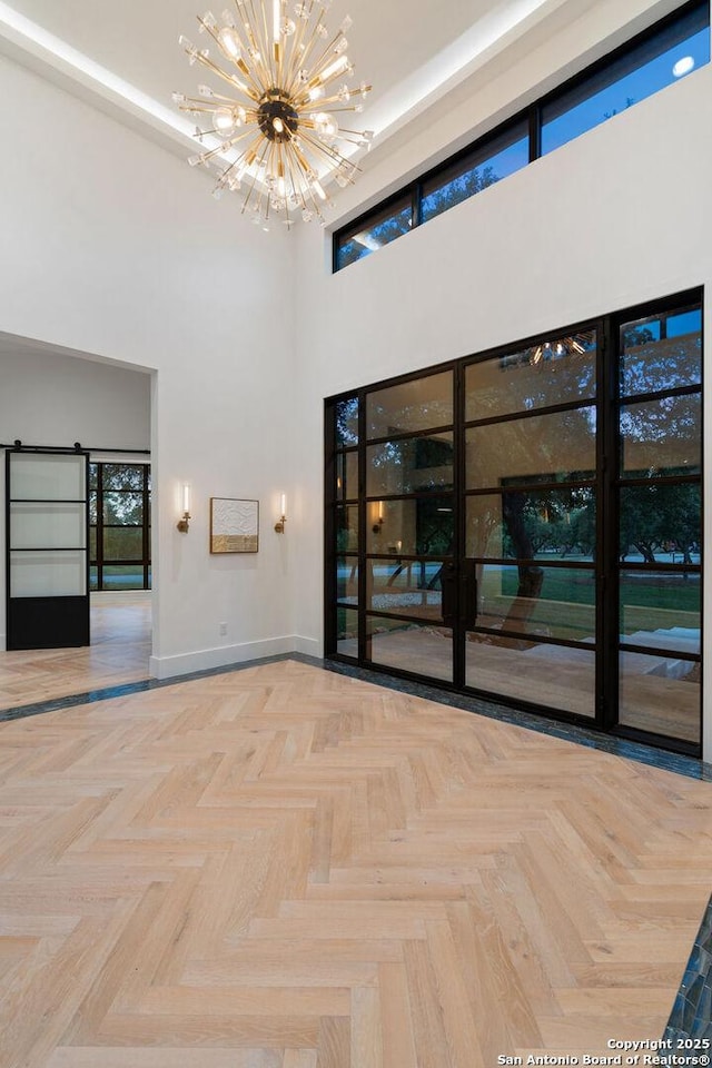 unfurnished room with a towering ceiling, baseboards, and a notable chandelier