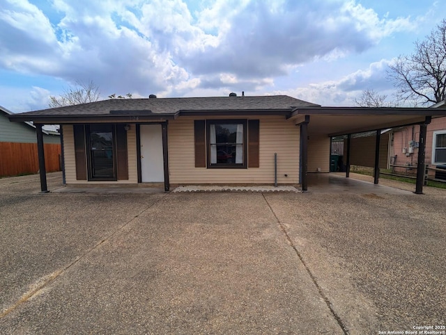 back of house featuring driveway, a shingled roof, fence, and a carport