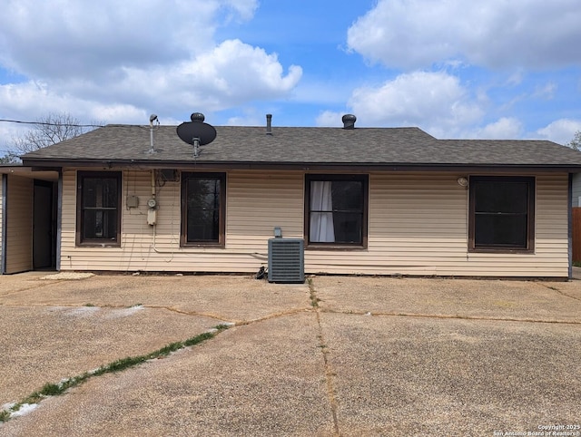 back of house featuring cooling unit and a shingled roof