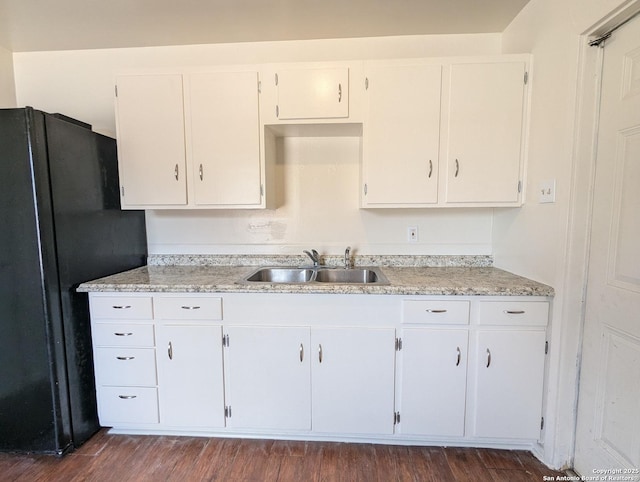 kitchen with dark wood-style flooring, white cabinets, a sink, and freestanding refrigerator