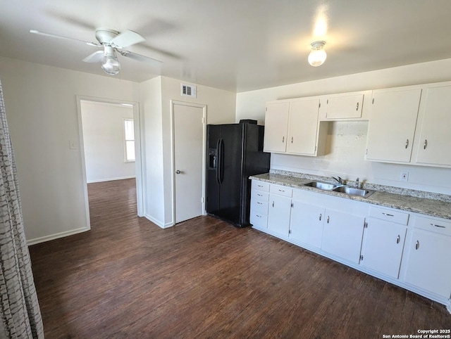 kitchen with white cabinetry, a sink, black fridge with ice dispenser, and dark wood-type flooring